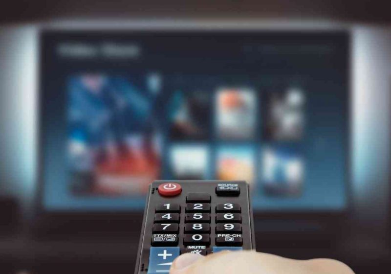 A photo of a person turning on the tv and streaming through various services