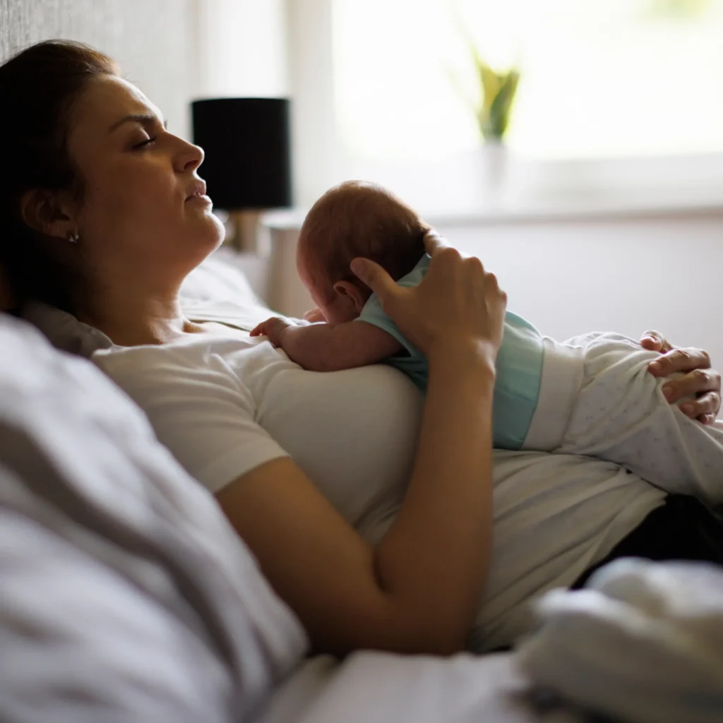 An exhausted mother holding her baby. Photo taken by damircudic from Getty Images.